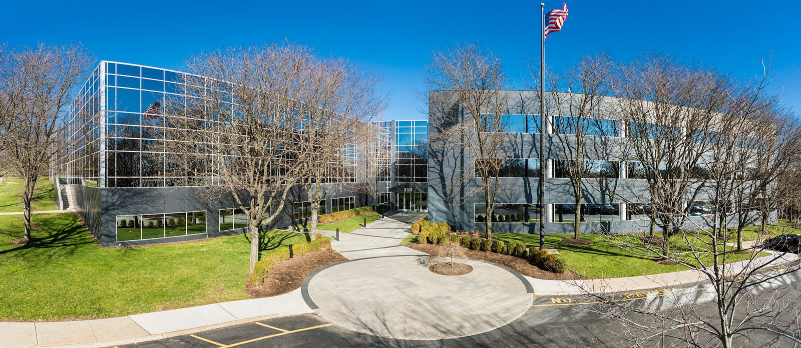 The Appraisal Economics offices at 115 West Century Road, Paramus, New Jersey: two connected glass and stone office buildings set back from a landscaped entrance